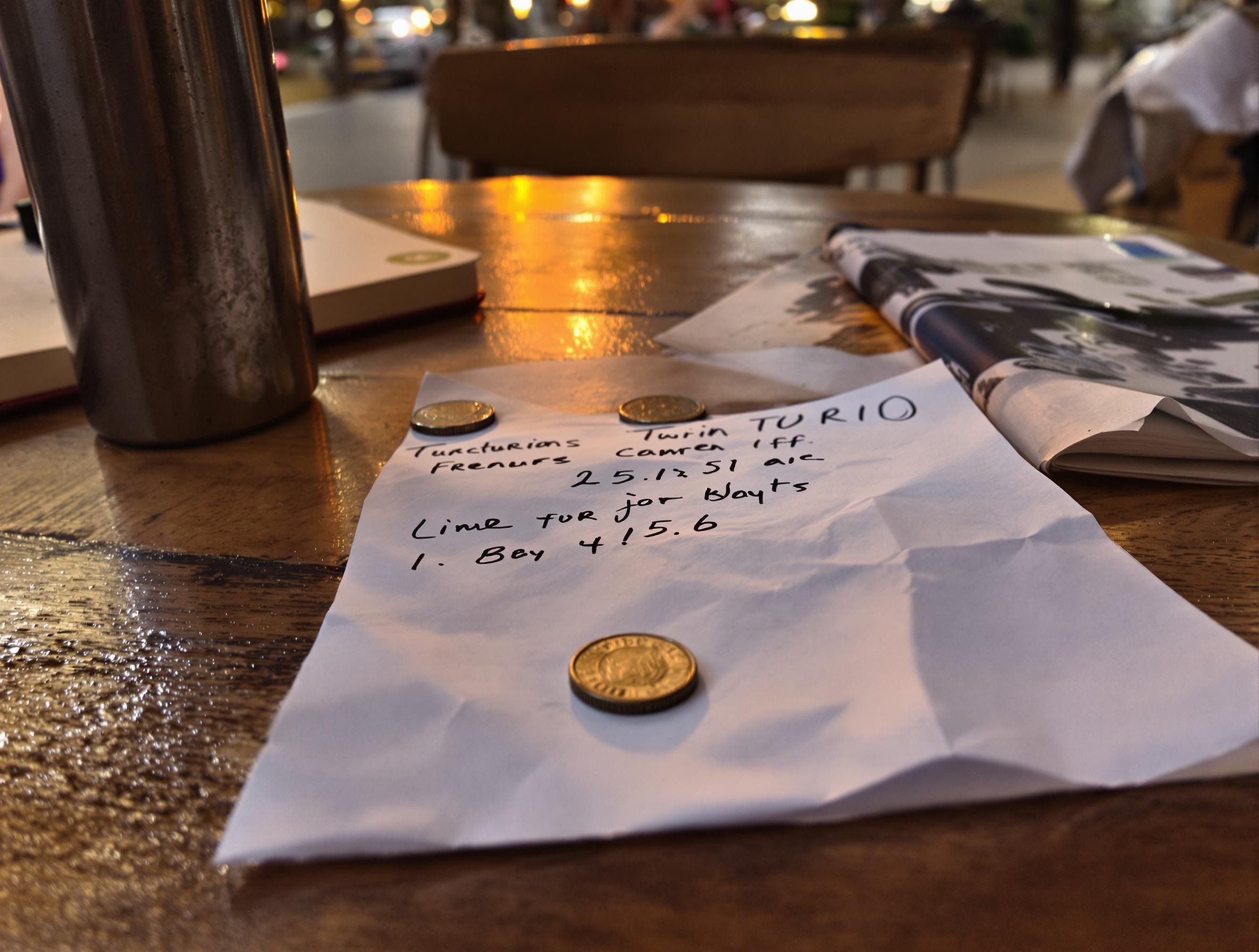 Addition dans une trattoria turinoise avec un Thermos, un carnet et des pièces