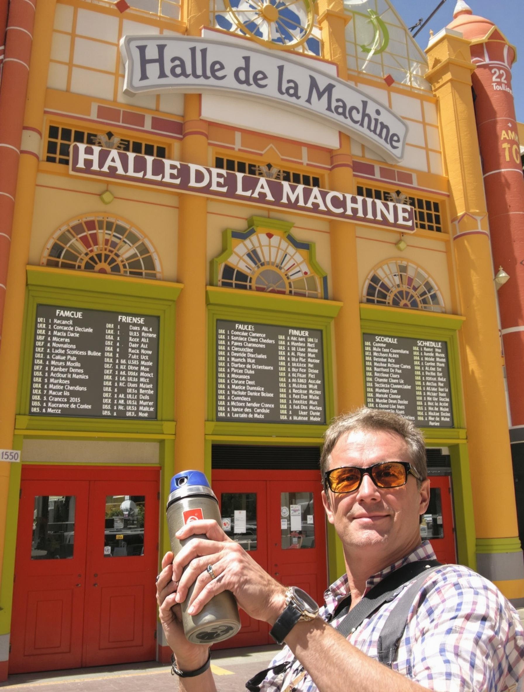 Visiteur facétieux et son Thermos devant la Halle de la Machine